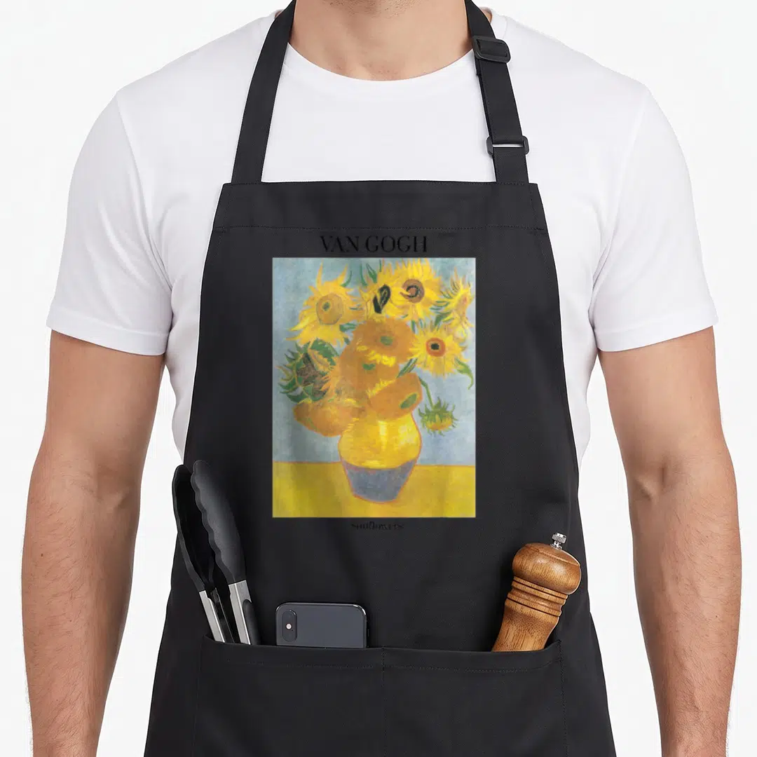 Sunflower vincent van gogh apron - VAN GOGH text above yellow sunflower painting with blue background and lower label — shown on a black cotton canvas apron against a white background