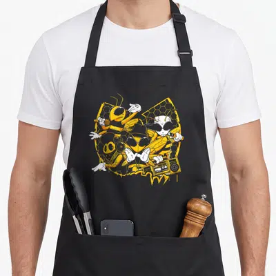 Hip bee apron - Four cartoon bees in hip-hop attire with boombox on yellow honeycomb — shown on a black cotton canvas apron against a white background