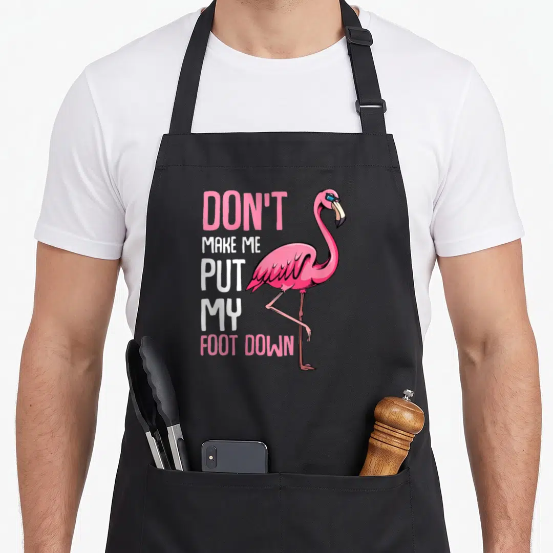 Foot animal pink flamingo apron - Pink flamingo standing on one leg beside stacked text reading Don't Make Me Put My — shown on a black cotton canvas apron against a white background