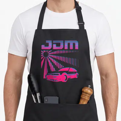 Synthwave car apron - Pink and blue JDM text over a stylized sun and car silhouette in retro art style — shown on a black cotton canvas apron against a white background
