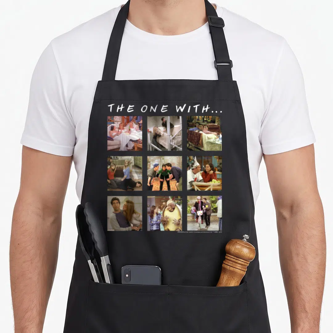 Character friends cooking apron - THE ONE WITH text above nine photo scenes in white brown blue yellow grid — shown on a black cotton canvas apron against a white background