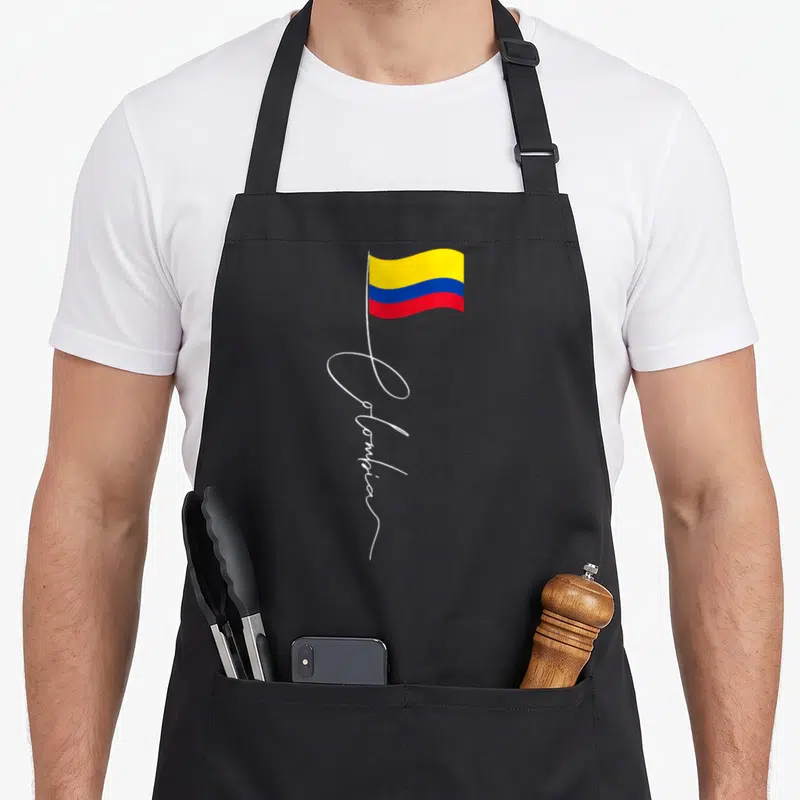 Heritage family aprons - Colombia flag with pole forming script text in yellow blue red white — shown on a black cotton canvas apron against a white background