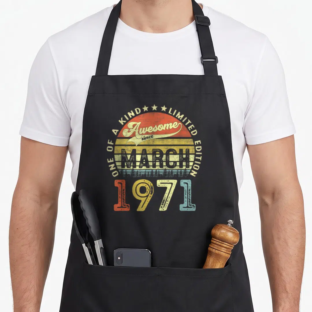March 50th birthday apron - Retro striped sun with ONE OF A KIND text and 1971 digits in red yellow blue white — shown on a black cotton canvas apron against a white background