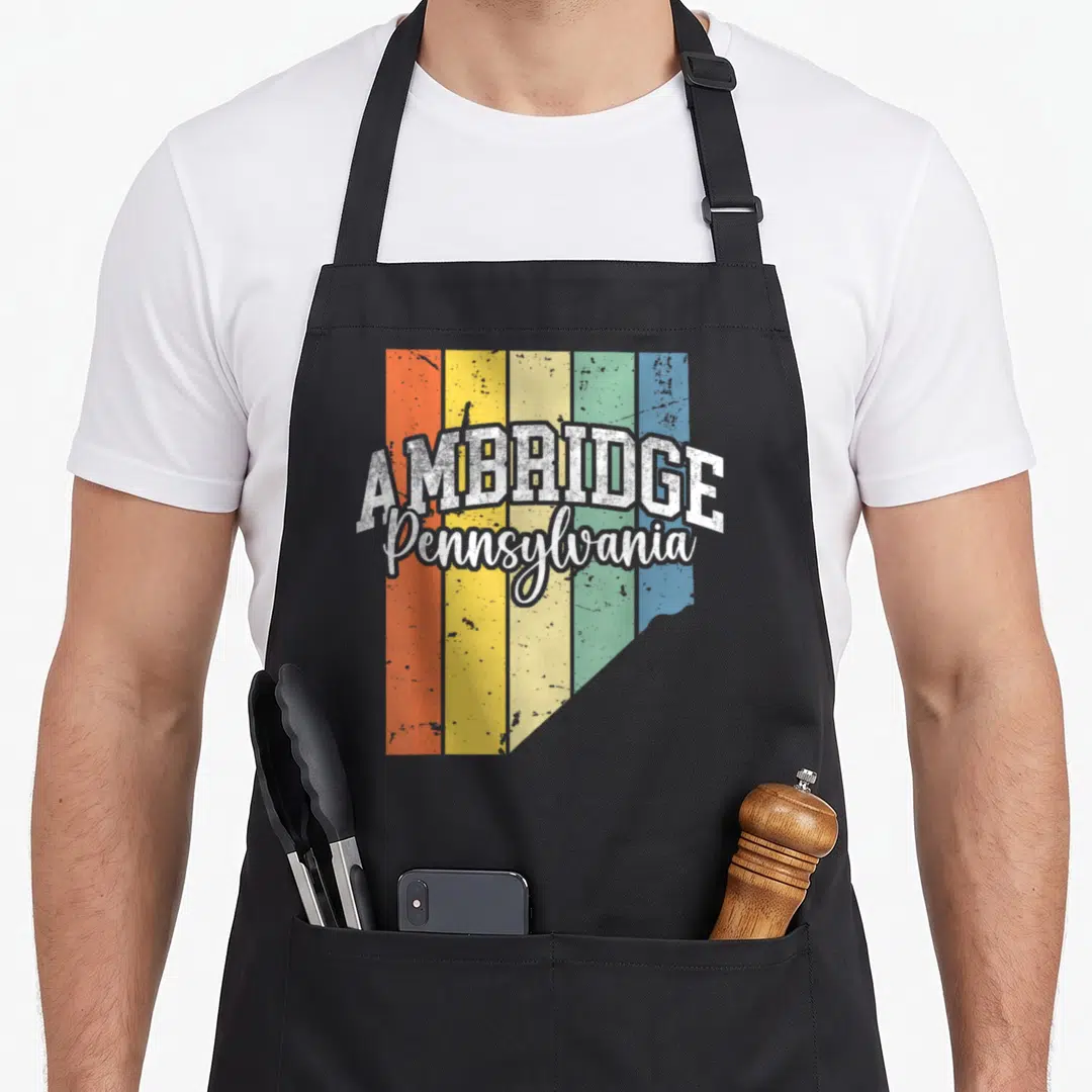 Ambridge pride apron - AMBRIDGE Pennsylvania text over five vertical colored stripes in a Beaver County shape — shown on a black cotton canvas apron against a white background