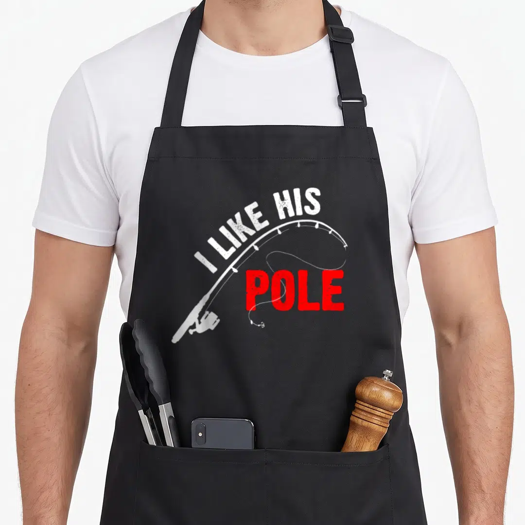 Fishing couple apron - I LIKE HIS POLE text over white fishing pole with red POLE below — shown on a black cotton canvas apron against a white background