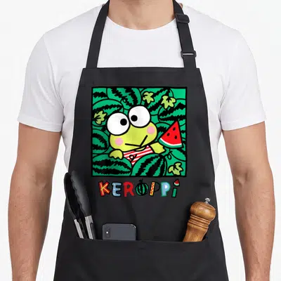 Keroppi watermelon apron - Cartoon frog holding red watermelon slice inside green patterned square with KEROPPI text — shown on a black cotton canvas apron against a white background
