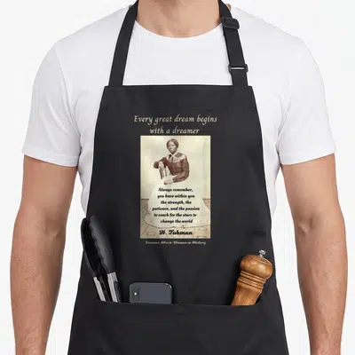 Tubman h apron - Sepia portrait of Harriet Tubman with inspirational quote about dreams and changing the world — shown on a black cotton canvas apron against a white background