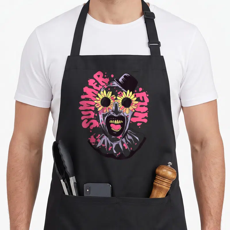 Summer clown aprons - Grey cartoon clown head with yellow sunflower sunglasses, black top hat, and pink text — shown on a black cotton canvas apron against a white background
