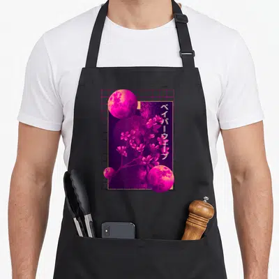 90s cherry print apron - Three pink moons and cherry blossoms over pink grid with vertical Japanese text — shown on a black cotton canvas apron against a white background