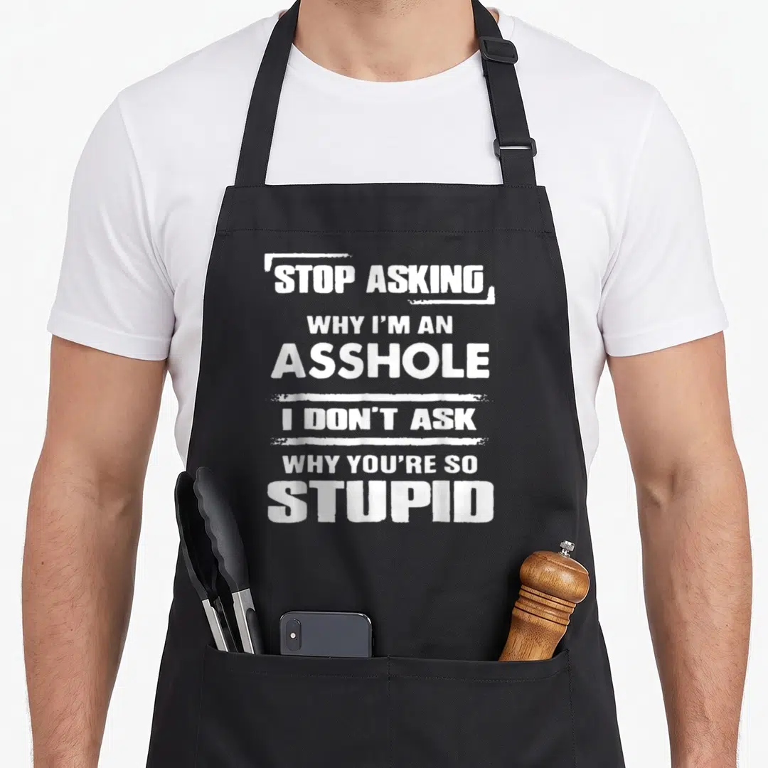 Asking novelty apron - White text reading Stop Asking Why I'm an Asshole I Don't Ask Why You're So Stupid — shown on a black cotton canvas apron against a white background