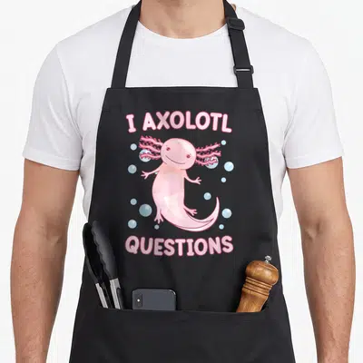 Question girl axolotl apron - Pink cartoon axolotl with blue bubbles and text I AXOLOTL QUESTIONS — shown on a black cotton canvas apron against a white background