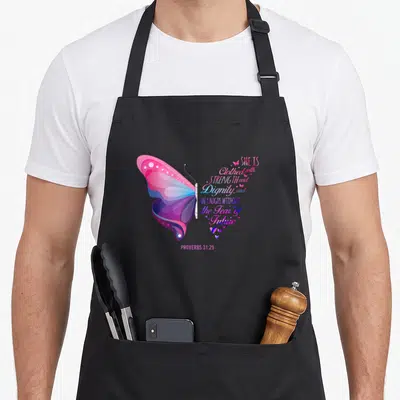 Christian proverb bible verse apron - Butterfly with pink purple blue wings next to Proverbs 31:25 text and small hearts — shown on a black cotton canvas apron against a white background