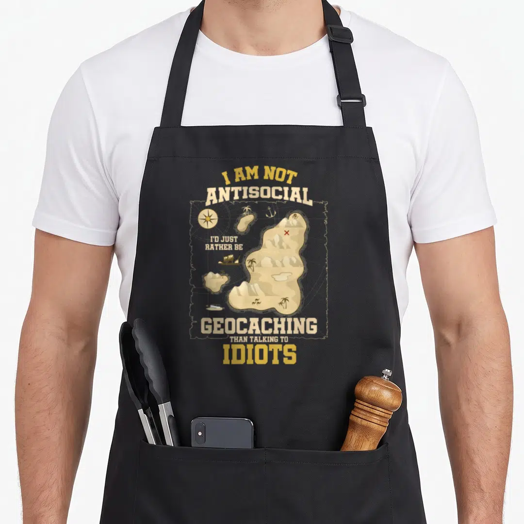 Geocaching antisocial apron - Retro treasure map with compass anchor and text I AM NOT ANTISOCIAL I'D JUST RATHER BE — shown on a black cotton canvas apron against a white background