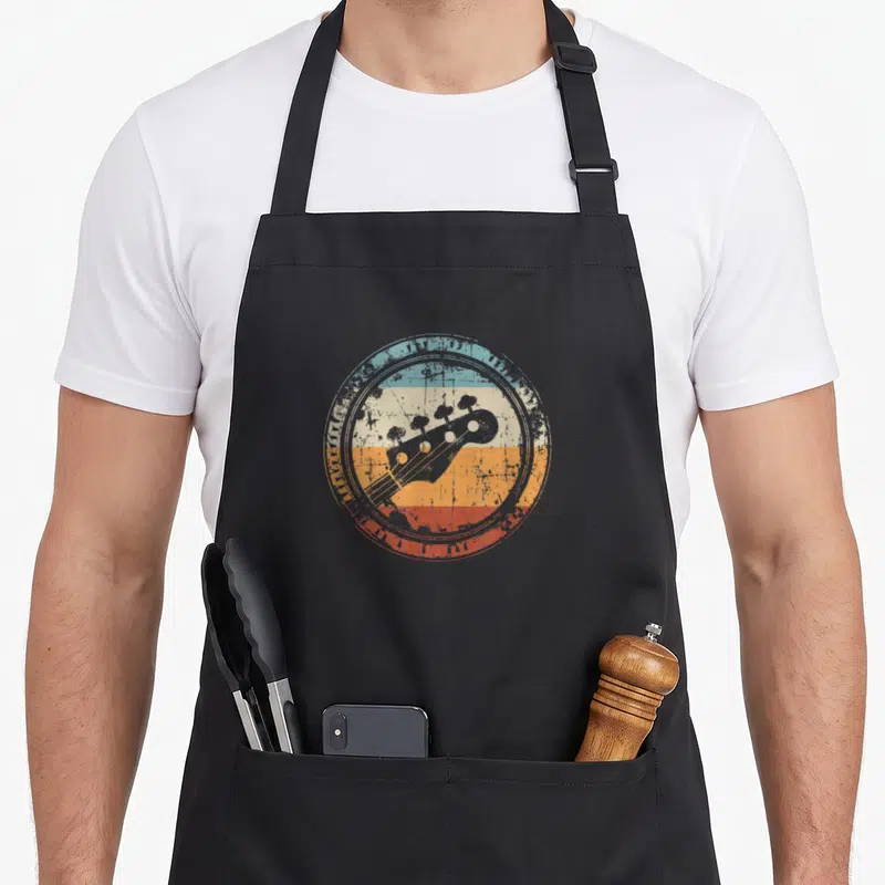 Bass bassist apron - Grey bass headstock silhouette over blue cream orange and red distressed stripes — shown on a black cotton canvas apron against a white background