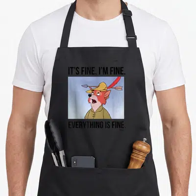 Fine crazy robin man apron - Cartoon fox with arrow through hat and IT'S FINE text on black apron — shown on a black cotton canvas apron against a white background