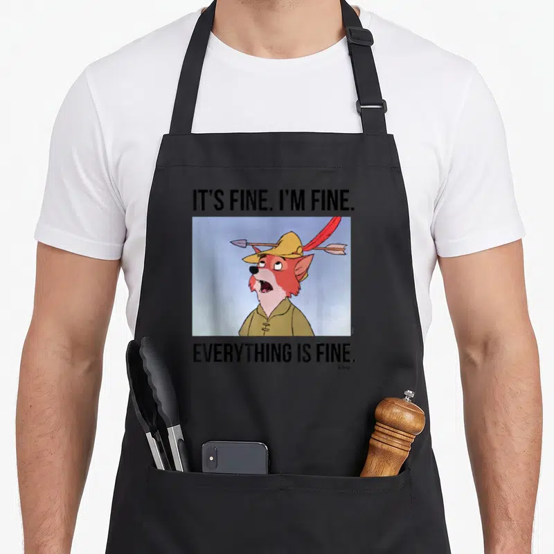 Fine crazy robin man apron - Cartoon fox with arrow through hat and IT'S FINE text on black apron — shown on a black cotton canvas apron against a white background