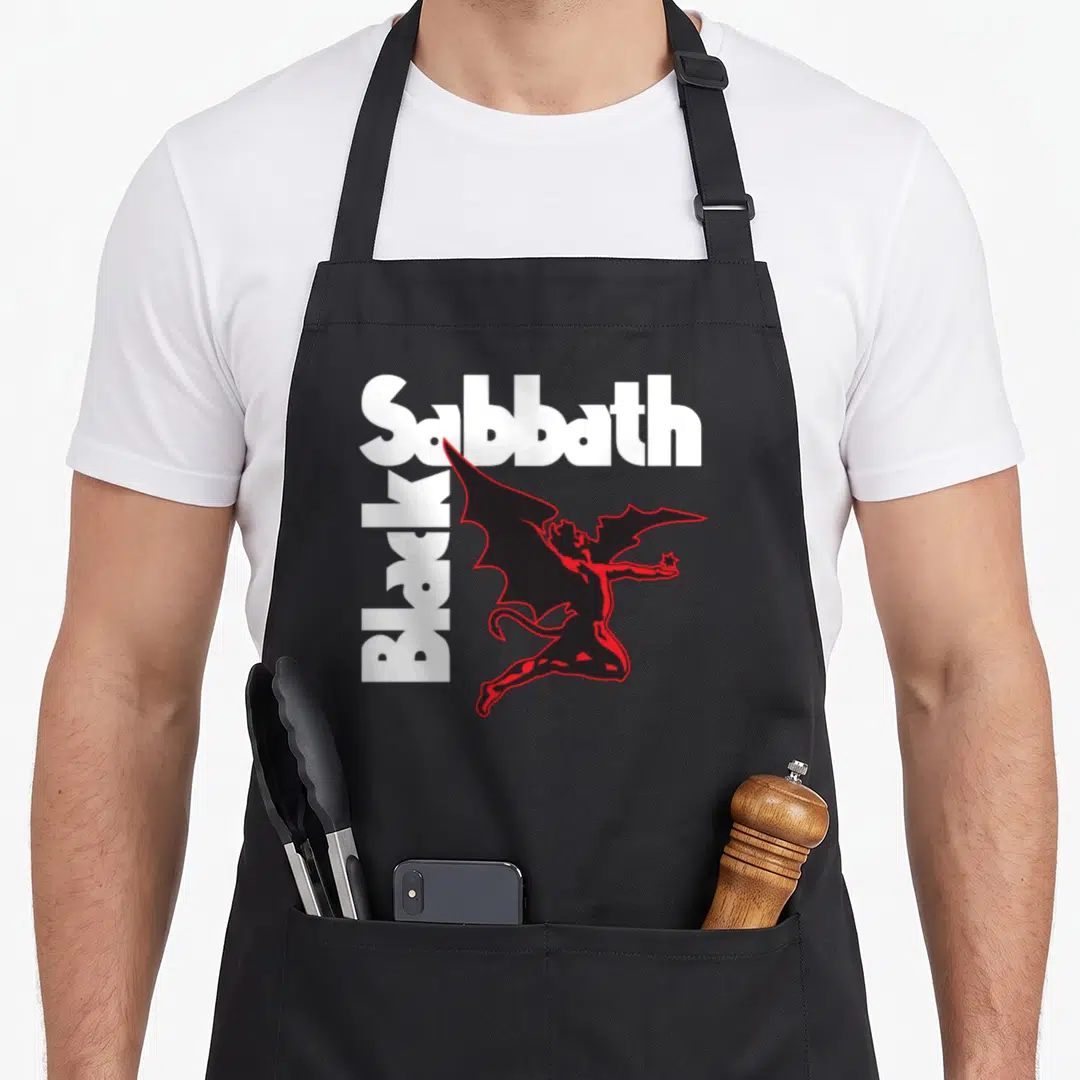 Funny creature black sabbath apron - White and red text with a black devil figure holding a star — shown on a black cotton canvas apron against a white background