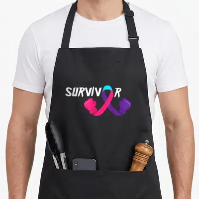 Cancer survivor thyroid apron - SURVIVOR text with looped ribbon in teal pink purple and two boxing gloves hanging below — shown on a black cotton canvas apron against a white background