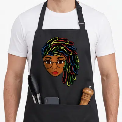 Dreadlock hair apron - Cartoon woman face with glasses and colorful dreadlocks in red yellow green blue — shown on a black cotton canvas apron against a white background