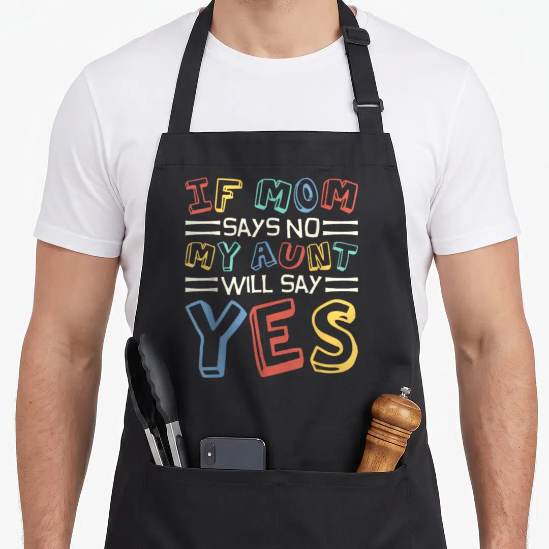 Toddler nephew apron - Stacked colorful text reading If Mom Says No My Aunt Will Say Yes in red blue yellow teal beige — shown on a black cotton canvas apron against a white background