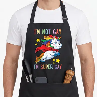 Unicorn gay pride apron - Cartoon white unicorn with rainbow mane red cape and stars framed by I'm Not Gay I'm Super — shown on a black cotton canvas apron against a white background