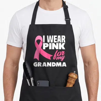 Funny grandma breast cancer awareness aprons - Pink ribbon and I WEAR PINK for my GRANDMA text in white and pink — shown on a black cotton canvas apron against a white background