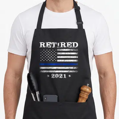 Retired thin retirement apron - Distressed white RETIRED text above blue line flag and 2021 with stars — shown on a black cotton canvas apron against a white background