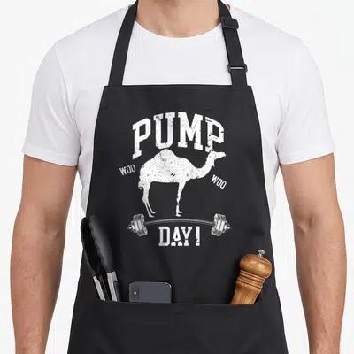 Pump training apron - White distressed camel silhouette on barbell with PUMP WOO WOO DAY! text — shown on a black cotton canvas apron against a white background