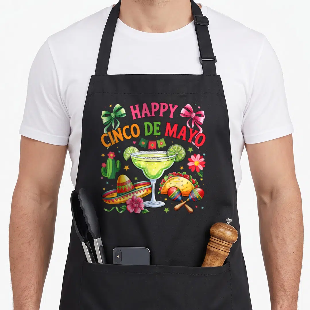 Funny cinco mexican apron - HAPPY CINCO DE MAYO text with margarita, taco, sombrero, maracas, cactus, and flowers — shown on a black cotton canvas apron against a white background