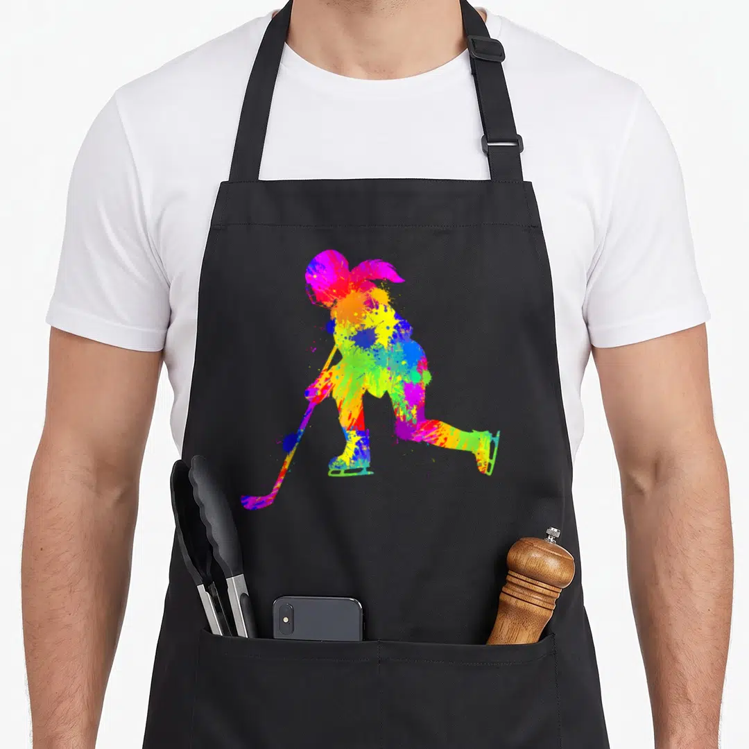 Funny youth hockey ice apron - Multicolored watercolor splatter silhouette of a hockey player on black fabric — shown on a black cotton canvas apron against a white background