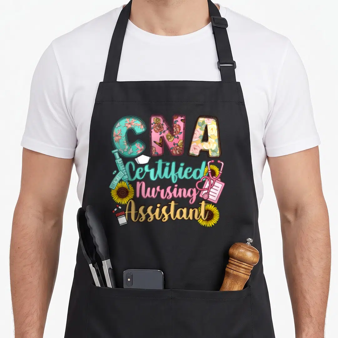 Certified assistant nursing aprons - CNA text with floral patterns, syringe, stethoscope, sunflowers, and stacked title — shown on a black cotton canvas apron against a white background