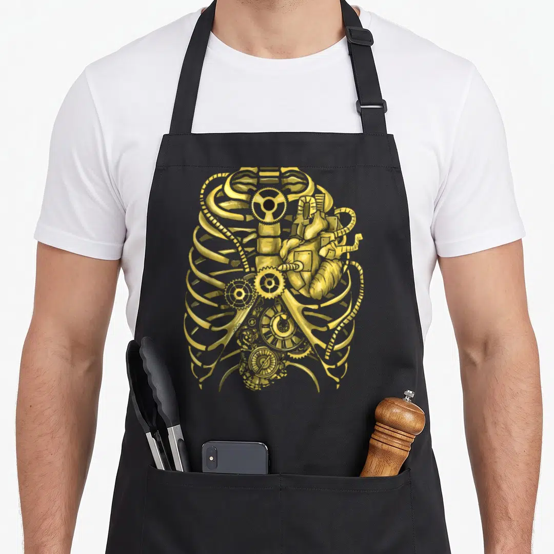 Steampunk mechanical apron - Realistic golden mechanical ribcage containing a brass heart and interlocking clockwork — shown on a black cotton canvas apron against a white background