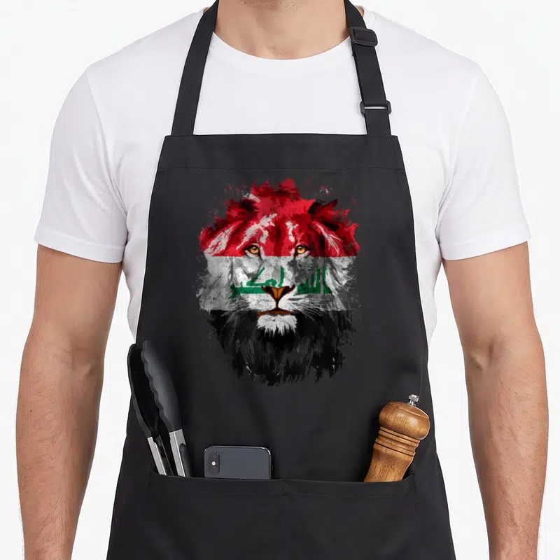 Iraq lion apron - Realistic lion head filled with red white black and green Iraqi flag colors and script — shown on a black cotton canvas apron against a white background