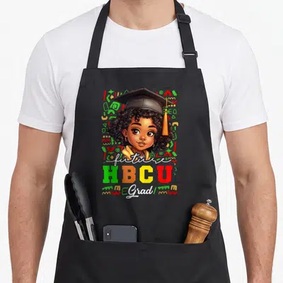 Graduation college apron - Cartoon graduate with cap surrounded by abstract shapes and text reading future HBCU Grad — shown on a black cotton canvas apron against a white background