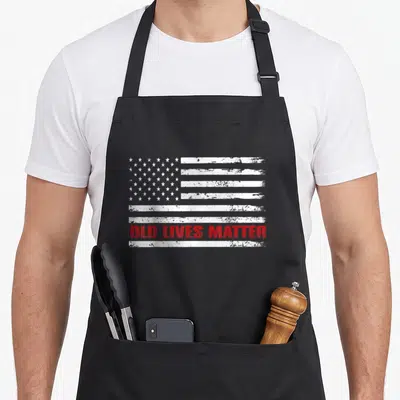 50th old lives matter apron - Distressed USA flag with white stars and red OLD LIVES MATTER text across stripes — shown on a black cotton canvas apron against a white background