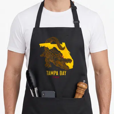 Aligator florida apron - Brown alligator over yellow Florida map with red star and centered text — shown on a black cotton canvas apron against a white background