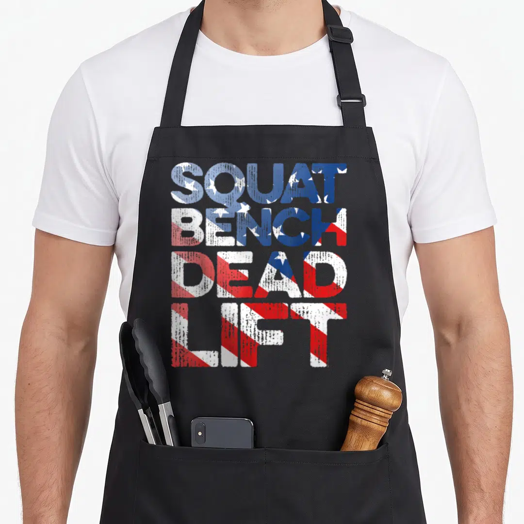 Squat training apron - Stacked SQUAT BENCH DEAD LIFT text in distressed blue white and red flag pattern — shown on a black cotton canvas apron against a white background