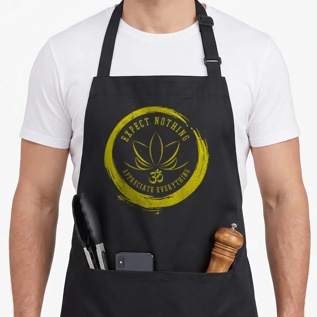 Buddhism nepal apron - Yellow distressed circle with lotus flower, Om symbol, and Expect Nothing Appreciate Everything — shown on a black cotton canvas apron against a white background