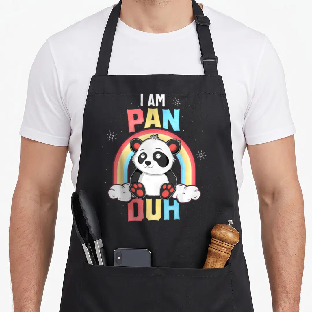 Pan rainbow apron - I Am Pan Duh text with cartoon panda under rainbow and two clouds — shown on a black cotton canvas apron against a white background