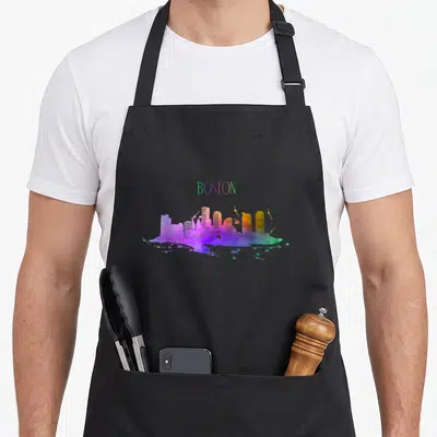 Watercolour pride apron - BOSTON text above a multi-colored watercolor city skyline in purple, blue, green, yellow — shown on a black cotton canvas apron against a white background