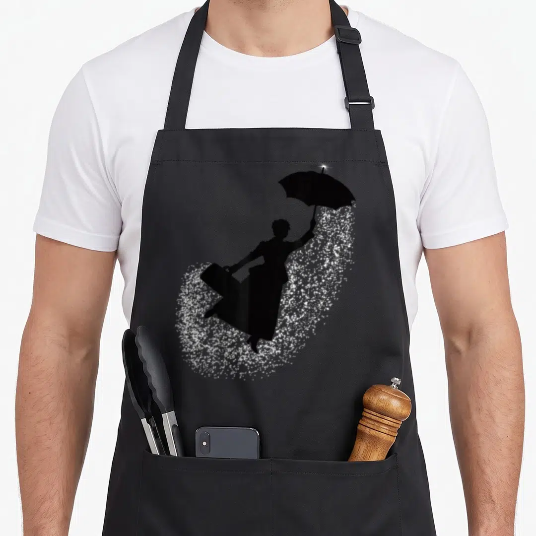 Magical flying apron - Black silhouette woman holding umbrella over white sparkles — shown on a black cotton canvas apron against a white background