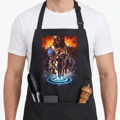 Endgame earth apron - Thanos head looms above Avengers heroes with logo at bottom in orange and blue photo style — shown on a black cotton canvas apron against a white background