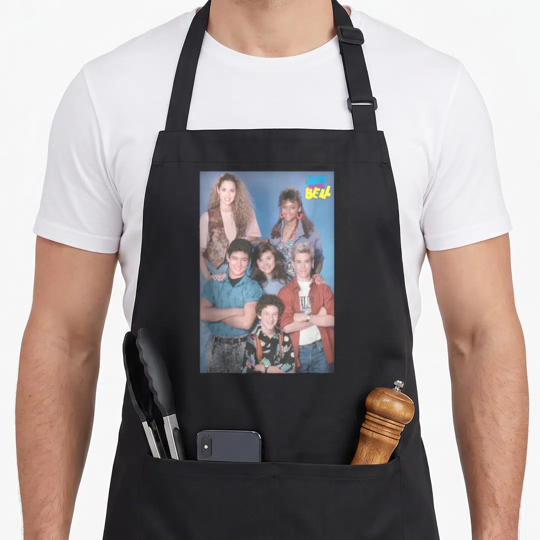 Saved novelty apron - Six people group photo blue background SAVED THE BELL logo pink yellow — shown on a black cotton canvas apron against a white background