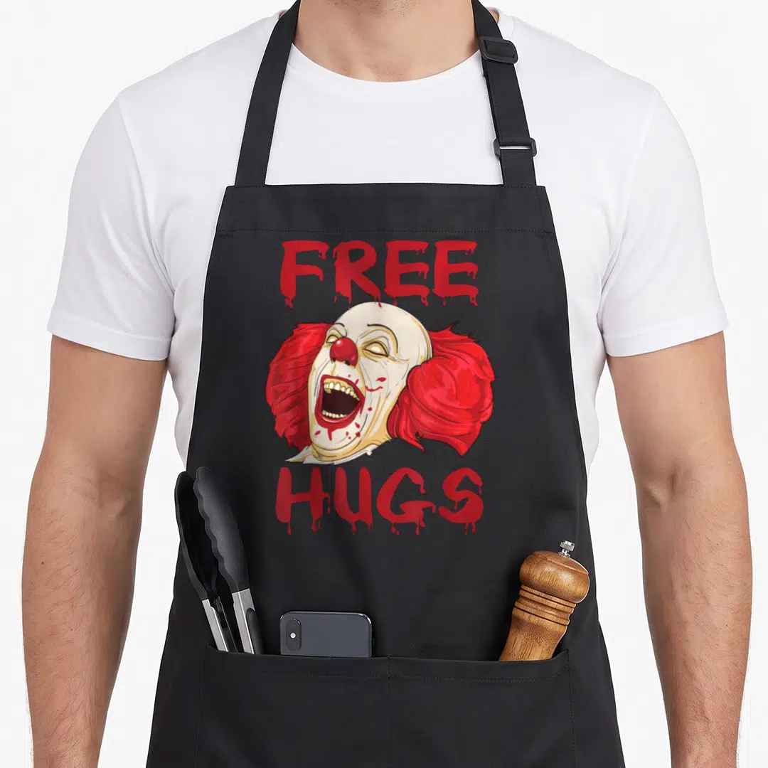 Free clown aprons - Screaming clown head between dripping red free and hugs text — shown on a black cotton canvas apron against a white background